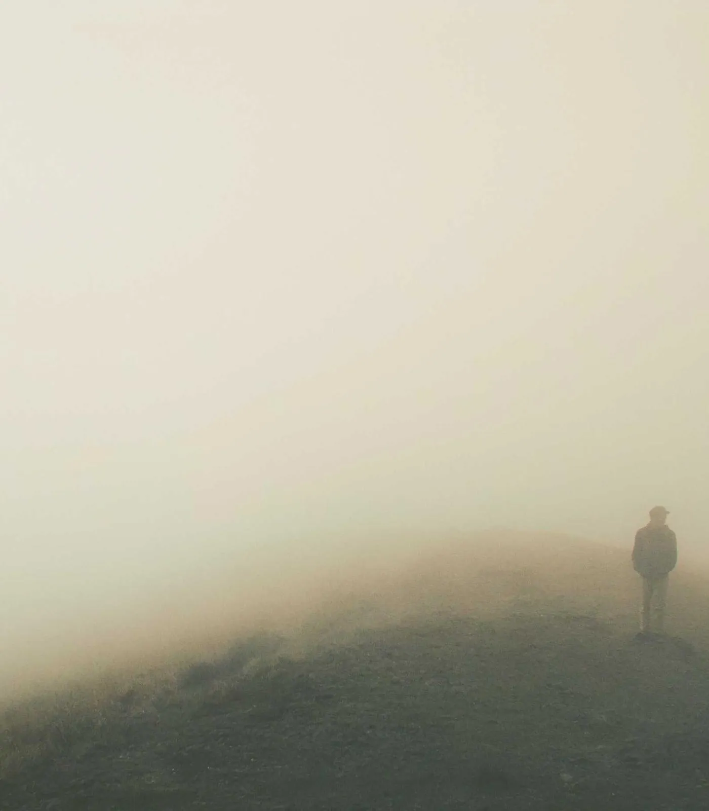 Una persona de pie en lo alto de una colina envuelta en niebla